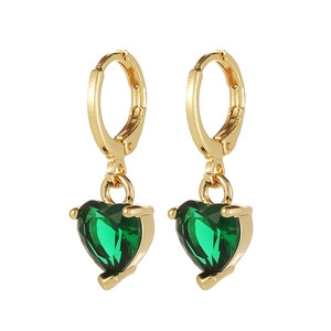 Détail de boucles d'oreilles huggie coeur émeraude verte avec monture plaquée or à 3 griffes