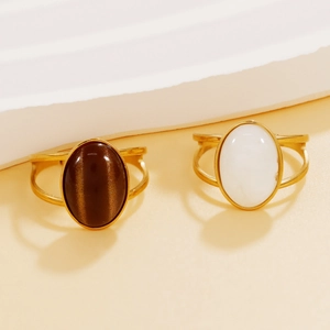 Vintage gold rings with oval brown cat-eye and white resin stones on white platform