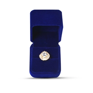 Detail of sunflower shaped gold ring with white gemstone in blue velvet box