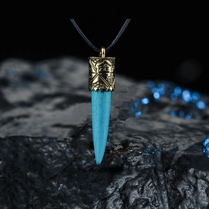 Détail macro du pendentif bohème en turquoise avec gravures ethniques dorées
