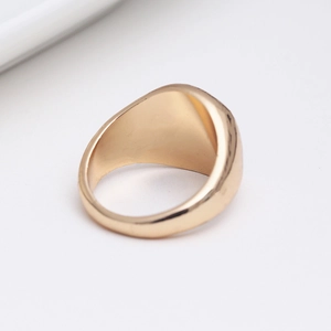 Vue macro d'une bague chevalière dorée avec finition miroir polie et bords arrondis