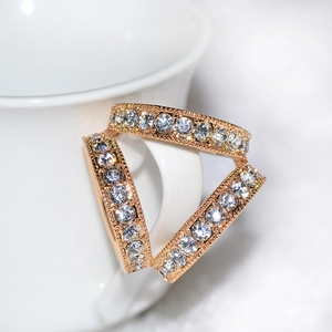 Macro de trois bagues dorées ornées de strass et bordure perlée sur une tasse blanche