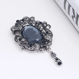 Vintage crystal brooch with oval grey gemstone and filigree metal frame in retro style