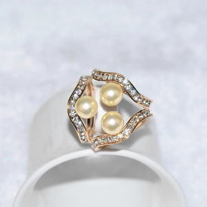 Détail d'une élégante broche à trois perles avec design de vagues pavées de zircons