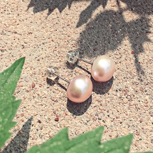 Dettaglio di orecchini con perle rosa e punzonatura S925 in argento sterling