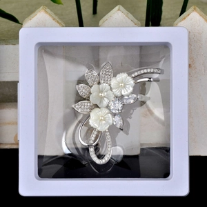 Macro detail of high-end floral brooch inside a white PE film suspension display box
