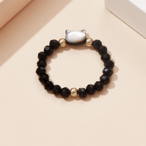 Detail view of elastic ring with black faceted beads and a shell cat head charm