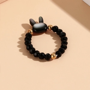 Macro detail of elastic beaded rabbit ring with faceted black beads and gold accents