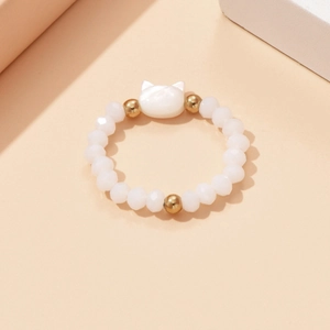 Close-up of elastic beaded ring with white cat charm and faceted white beads
