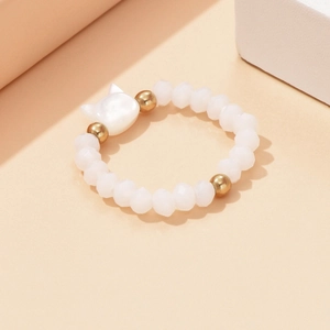Detailed macro view of white faceted beads with a cat-shaped shell charm and gold accents