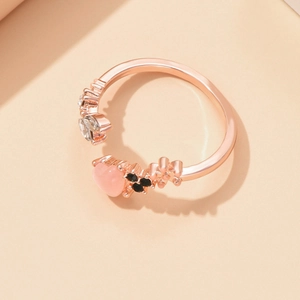 Détail macro d'une bague ouverte or rose avec cœur en œil de chat rose et strass