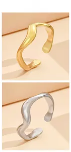 Nahaufnahme unregelmäßiger Wellenringe in Gold und Silber mit minimalistischem Design