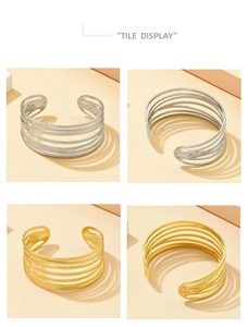 Detail view of multi-layer gold and silver stainless steel open bracelets on a sleek surface