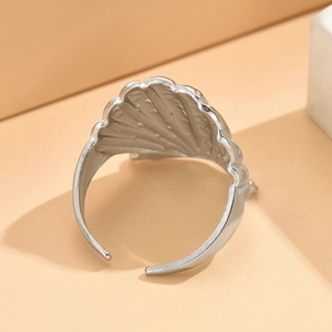 Verstellbarer Muschelring aus Silber-Edelstahl auf einem orangefarbenen Hintergrund