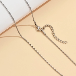 Collier élégant en acier inoxydable avec fermoir mousqueton réglable sur socle moderne