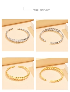 Detail view of twisted rope texture on C-shaped open bracelets in gold and silver