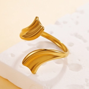 Bague spirale dorée avec texture plissée sur surface de pierre blanche et fond beige