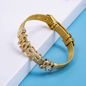 Adjustable gold mesh bracelet with sparkling XOXO and bow charms on white display