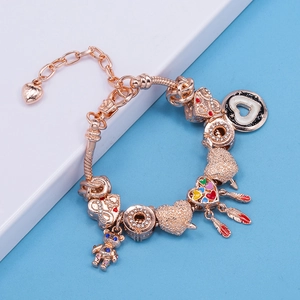 Bracciale a maglia snake oro rosa con ciondoli cuore, orso e piuma su sfondo bicolore