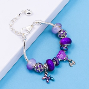 Detailed macro view of purple crystal glass beads and enamel charms on a silver snake chain