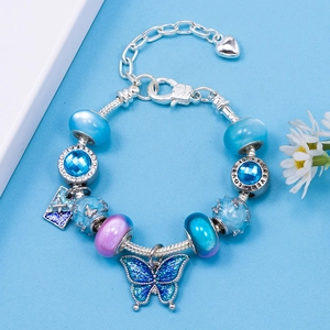 Detailed view of DIY charm bracelet with blue glass beads and hollow butterfly pendant