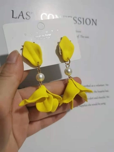 Macro shot of 925 silver post earrings with yellow matte petals and central pearl