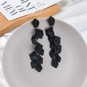 Macro detail of long black matte petal drop earrings on a minimalist display tray