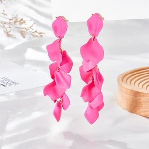 Macro detail of layered matte rose petals on long dangling earrings in vibrant flamingo pink