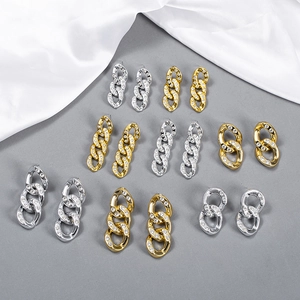 Golden and silver Cuban chain earrings set with shimmering crystals and elegant silk background
