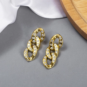 Close-up of gold chain earrings with sparkling white crystals on polished metal rings