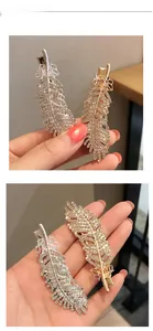 Detail of feather-shaped alloy hair clips with rhinestones and ribbon bows in gold and silver