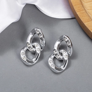 Macro detail of silver-tone interlocking link earrings with sparkling crystal pavé setting
