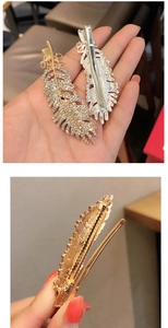 Detail of feather-shaped hair clips with sparkling rhinestones and polished metal finish