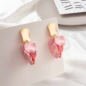 Detailed close-up of pink petal drop earrings with gold hooks on white satin