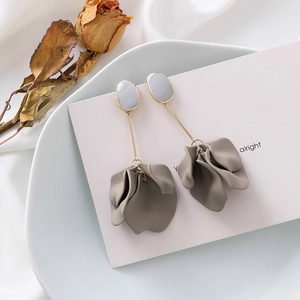 Close-up of elegant long grey floral earrings with gold stems on a white satin background