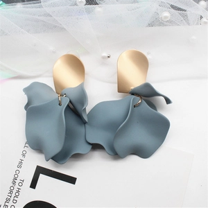 Detailed close-up of golden oval studs and blue-grey matte resin flower petal earrings