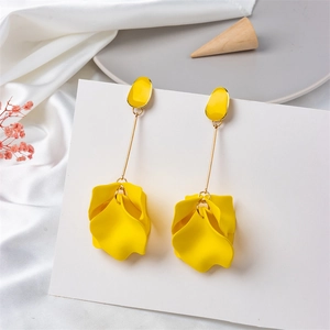 Detailed view of yellow floral drop earrings on elegant white silk and ceramic plate