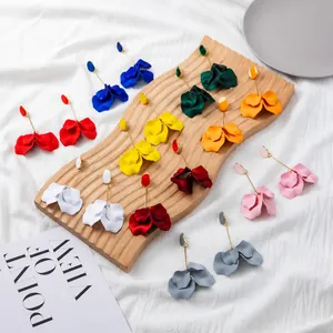 Detail showing long matte colorful petal earrings on a wooden display stand