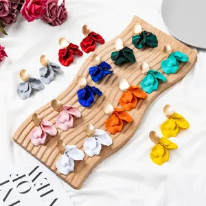 Detailed array of multi-colored matte petal drop earrings on a wooden display board