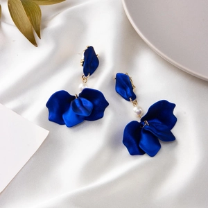 Detail of dark blue petal earrings with white pearl accent on silk background