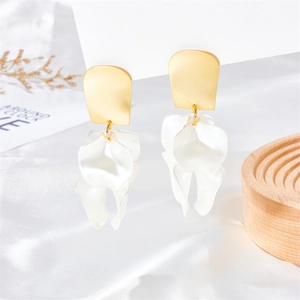 Detail view of artistic petal earrings with gold frosted studs on a silk background