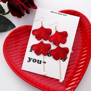 Detailed view of red ginkgo leaf earrings with gold chain and white pearl drop