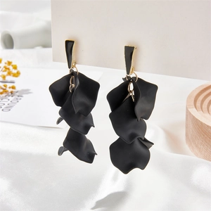 Macro shot of tiered black matte petal pendant earrings with gold connectors on a card