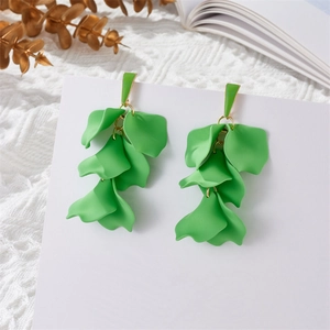 Close-up of green leaf tassel earrings with gold hooks on a white decorative lace background