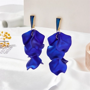 Detailed view of layered deep blue petal tassel earrings with gold trim on white satin