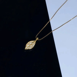 Collana con pendente a foglia dorata con cristalli bianchi su catena in acciaio titanio
