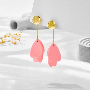 Detail view of pink petal drop earrings with gold metal studs on white fabric base