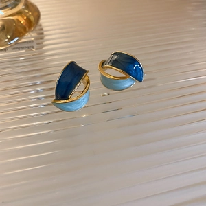 Dettaglio di orecchini vintage in smalto bicolore con design a nodo dorato a forma di C