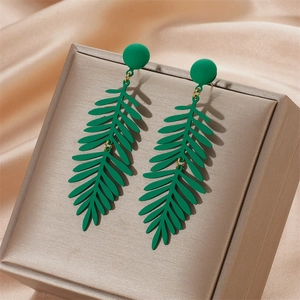 Green leaf earrings with matte finish on golden display box and silk fabric background