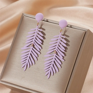 Elegant purple matte palm leaf earrings on luxury champagne silk display